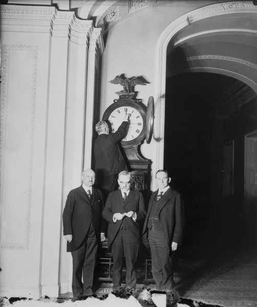 U.S. Senate Sergeant at Arms Charles P. Higgins turns the Ohio Clock forward for the first Daylight Saving Time in 1918. Senators William M. Calder (NY)